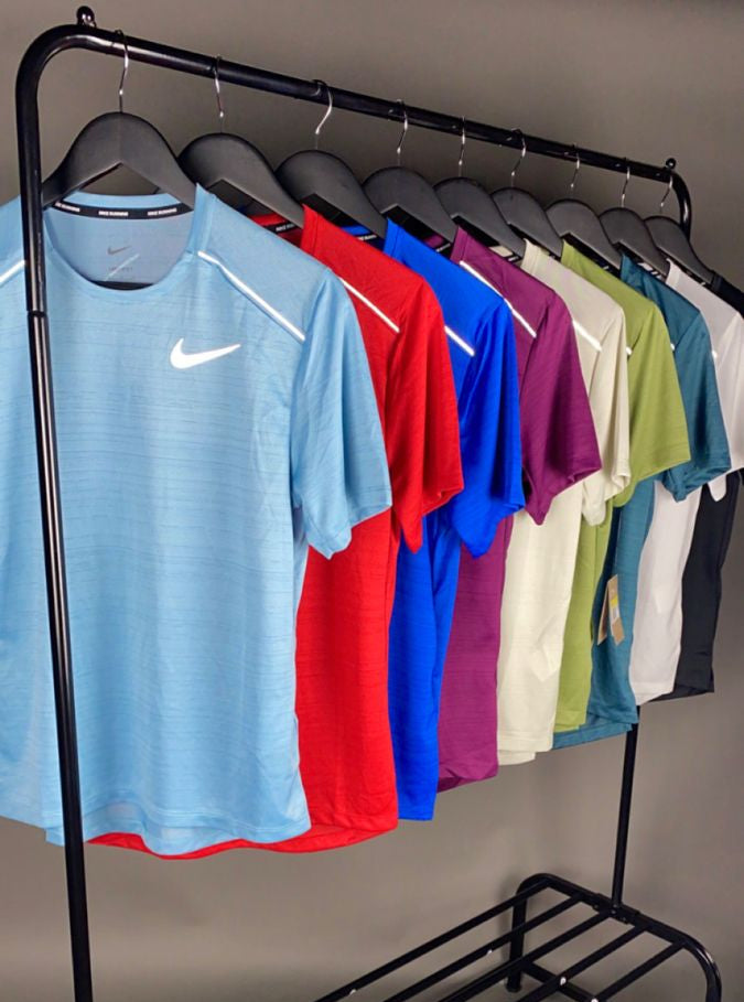 Black clothing rack with colorful shirts on hangers against a neutral background